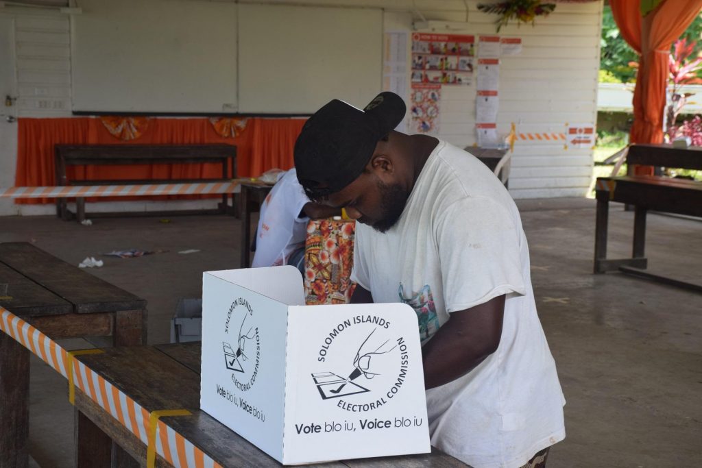 A voter marks his ballot paper before voting at Komuvatha polling station