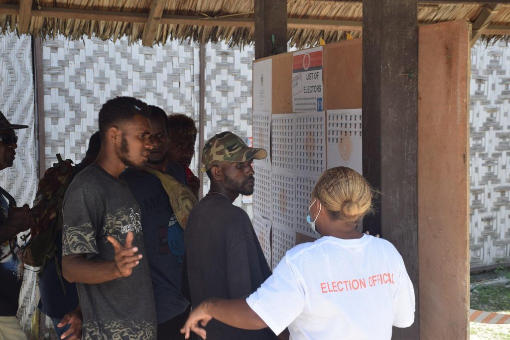 An election official guides the voters to check for their names