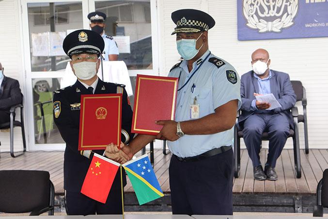 Commissioner Zhang of the China Police Liaison Team and Commissioner Mostyn Mangau of the RSIPF with the certificates of handover at Rove Police HQ